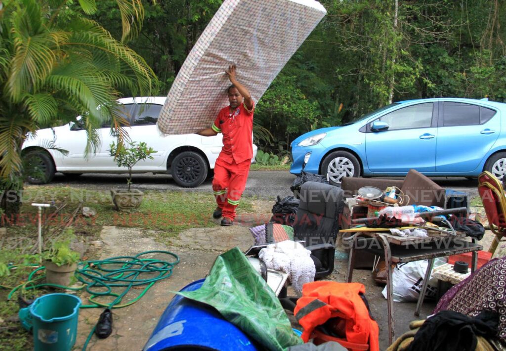 A Sangre Grande corporation worker delivers a mattress to resident Nicole Ali on Mandillon Road, Sangre Grande after her house was flooded out on Tuesday.