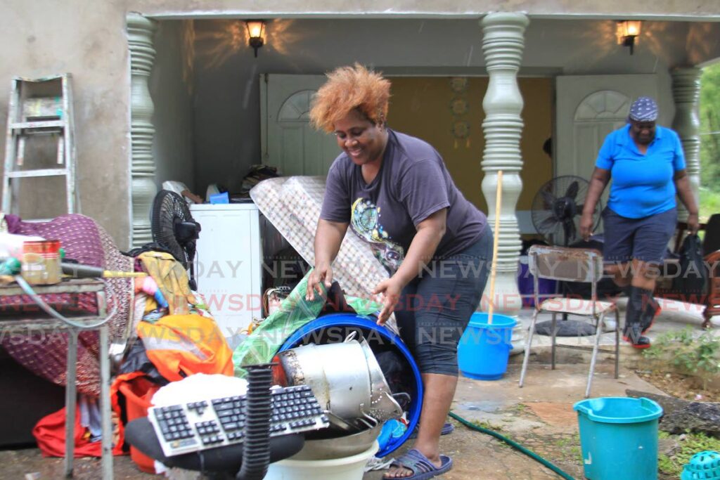 Nicole Ali puts her belongings outside after they were damaged by flood waters on Mandillon Road, Sangre Grande, on Wednesday. - Photo by Ayanna Kinsale