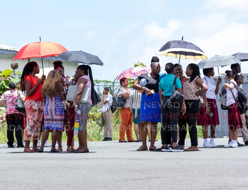 Teachers and students of Bishops High School, Scarborough, Tobago, gather at their muster point on Friday after school officials received an e-mailed bomb threat.  - David Reid