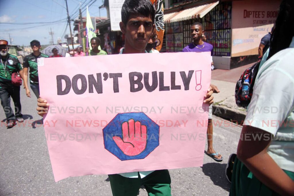 A student holdS up a placard as he took part in the  community-oriented police South Western Division peace walk through the streets of Siparia on Friday. - Lincoln Holder