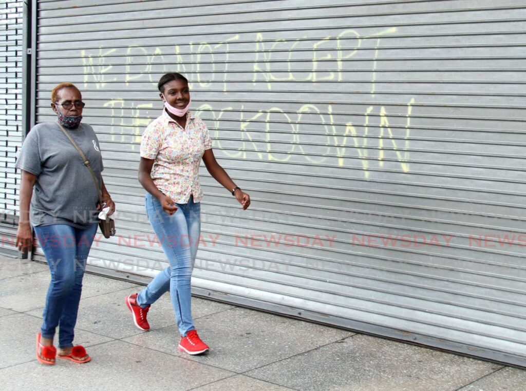 Two women walk past a shuttered business in Port of Spain during one of the pandemic lockdowns on April 30, 2021. - FILE PHOTO/AYANNA KINSALE