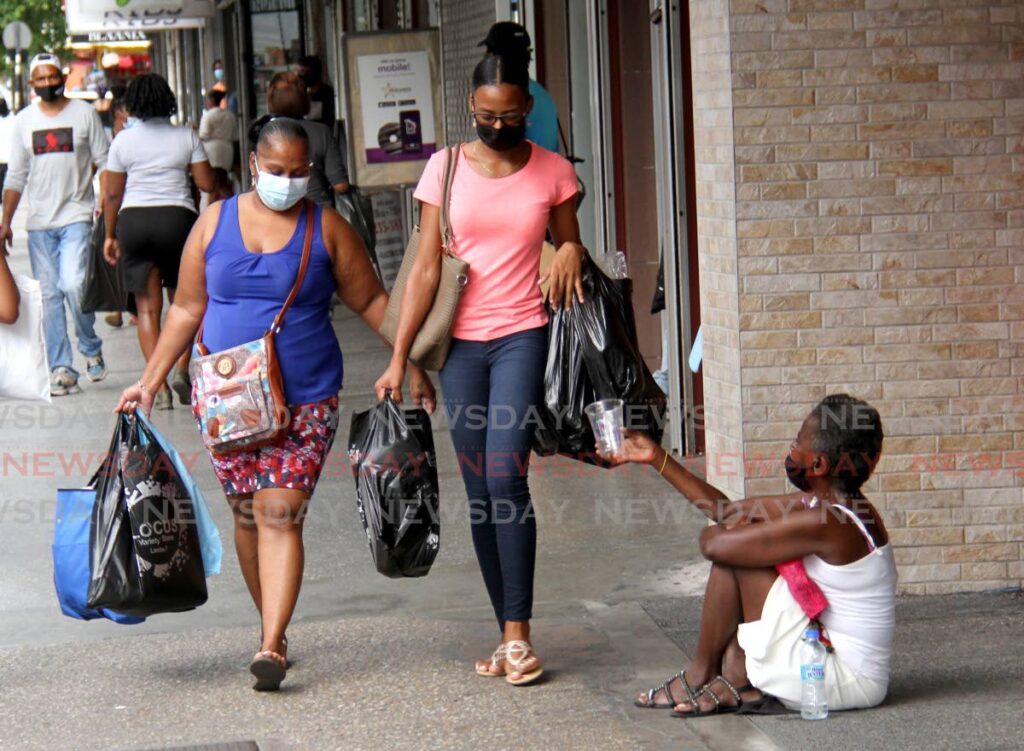 In this September 25, 2021 file photo, members of the public, including a woman in need, wear masks, in Port of Spain, as part of a mandatory public health measure for covid19. The WHO on Friday announced the pandemic is over. - FILE PHOTO/AYANNA KINSALE