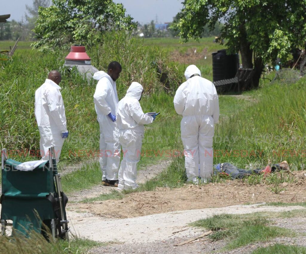 CRIME SCENE: Police crime scene investigators at the lot of land behind the Munroe Road SDMS Hindu Primary School after Ronnie Pierre was shot dead on Monday morning. PHOTO BY ANGELO MARCELLE - 