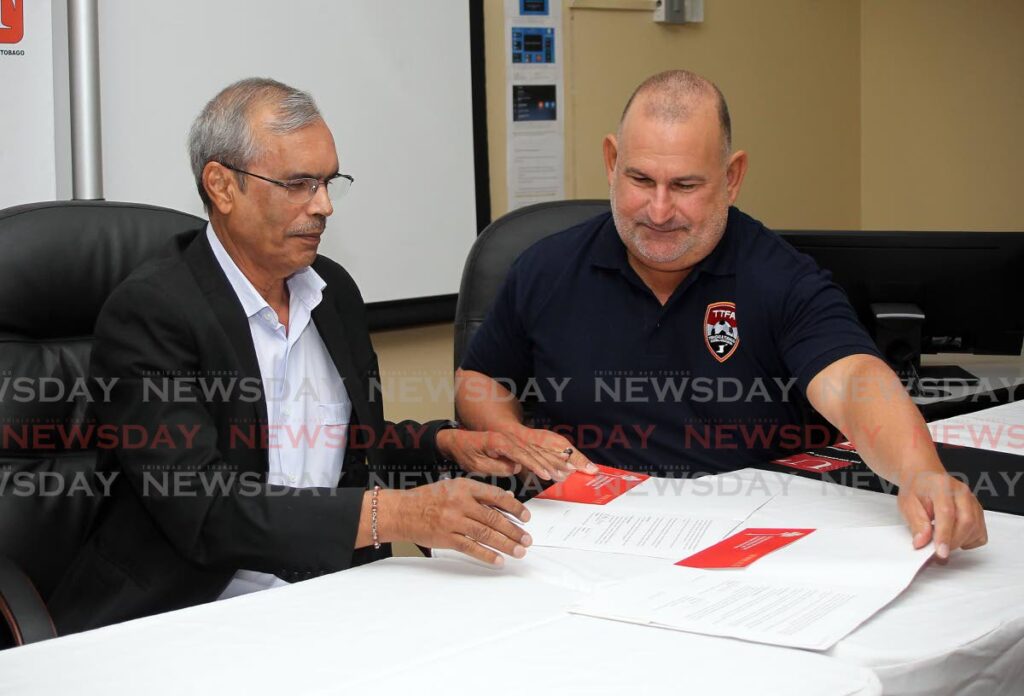 University of Trinidad and Tobago president Prakash Persad, left, signs an MOU with Robert Hadad, chairman of the FIFA-installed TT Football Association normalisation committee at UTT Chaguanas campus on Tuesday. - Photo by Lincoln Holder