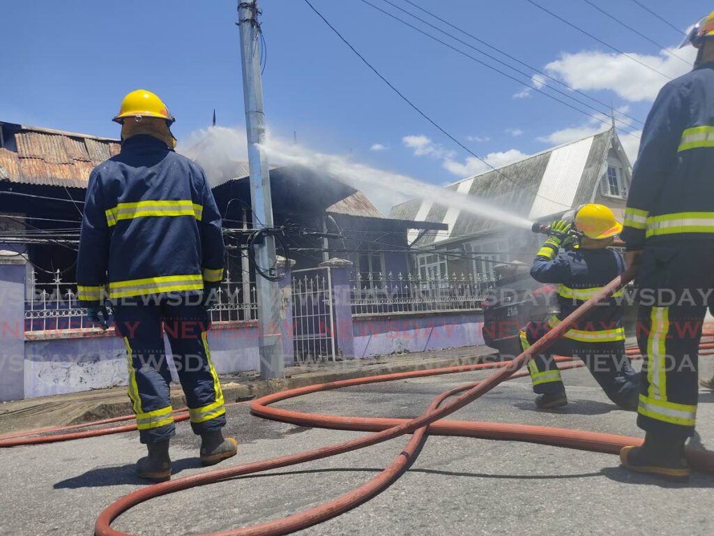 A fire officer aims a stream of water at a fire on the roof of an abandoned building on Shine Street, Port of Spain, on Monday morning. 
No one was injured in the blaze.  - Photo by Shane Superville