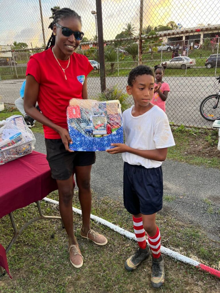 Organiser Denice Dedier presents a hamper to top goalscorer Tyreke Mendoza of Maguaya at the prize-giving ceremony for the Seed of Greatness Biche Football Development School's under-11 tournament.