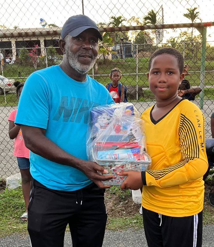Emray Grant of Maguaya collects the hamper for Best Goalkeeper at Seed of Greatness Biche Football Development School's under-11 tournament.