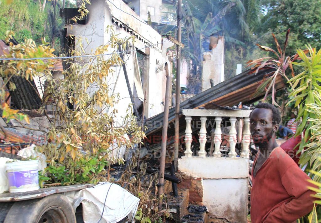 A Petit Bourg resident stands near his neighbour's house was destroyed by fire on Church Street Extension, Petit Bourg. - AYANNA KINSALE