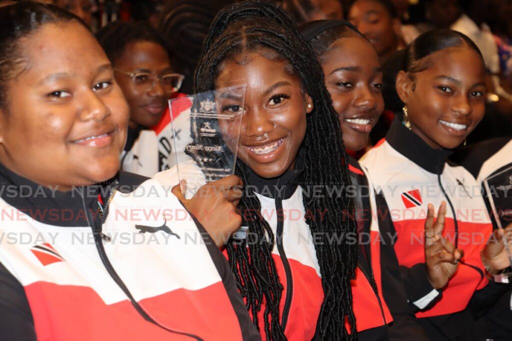 Tobago sprinter Alexxe Henry, second from left, smiles on Thursday while holding a plaque at the Hilton Hotel, St Ann's, at a ceremony hosted by the Ministry of Sport to honour national junior athletes.  - ROGER JACOB