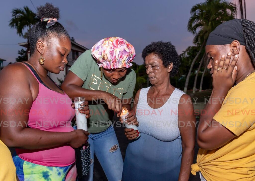 Lydia Thomas, second from right, and relatives light candles in memory of her grandson Hakeen Thomas at the area in Mt Pleasant, Tobago where he was killed on May 9. - David Reid