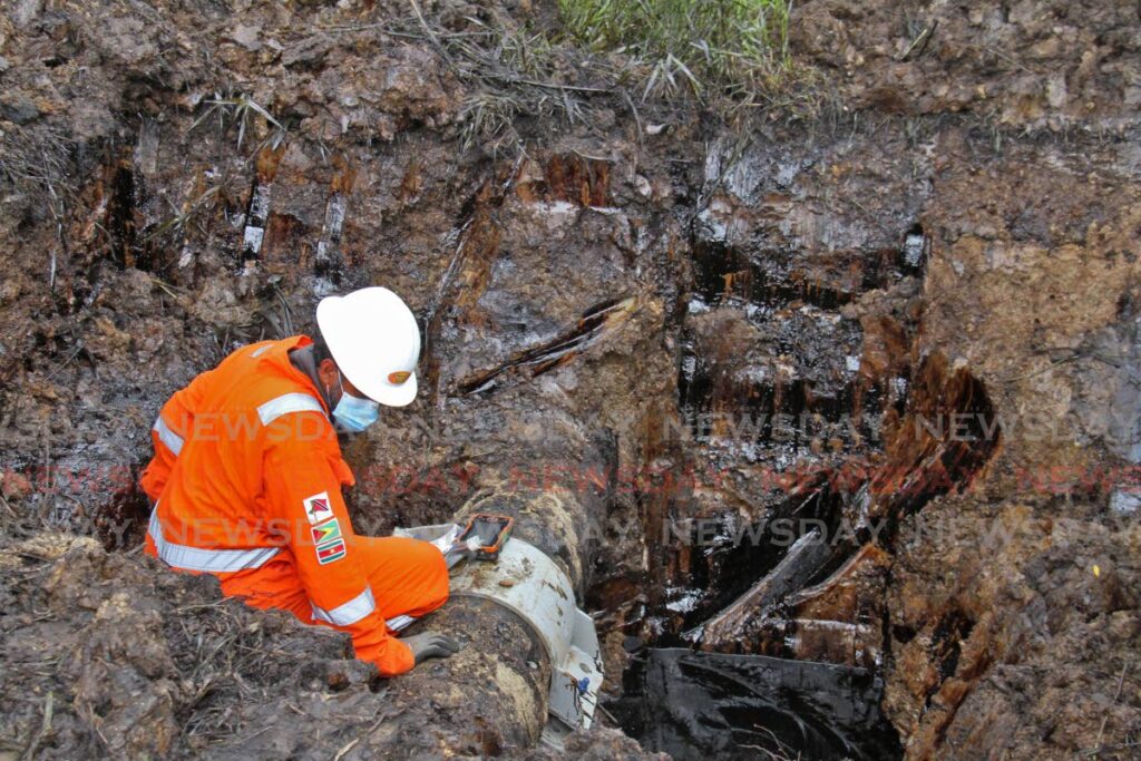 A Heritage Petroleum Co Ltd worker on Monday inspects an oil pipeline which ruptured at Masahood Village, Fyzabad on Sunday. - Marvin Hamilton