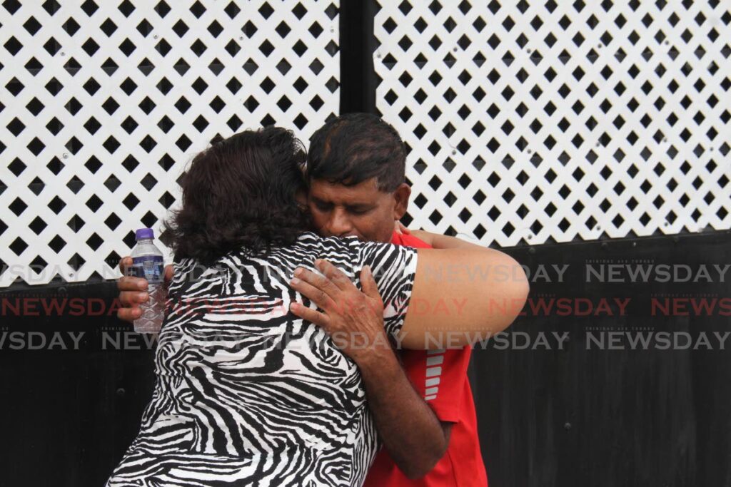 CONSOLED: Frankie Rajkumar is consoled by a woman on Monday at his Phillipine, South Trinidad home three days after his son Richard was fatally shot. PHOTO BY MARVIN HAMILTON   - 