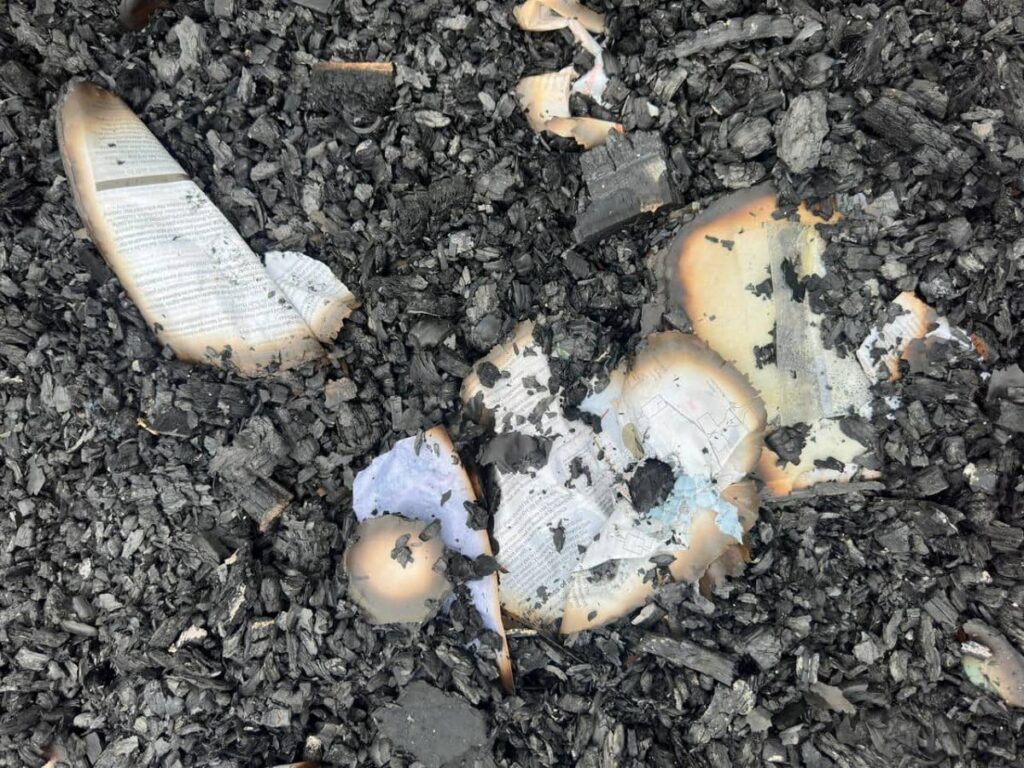 Burnt pages of a book on the ground after a fire razed through the dormitory of the  Mahdia Secondary School, Guyana killing at least 19 people. - News Room Guyana
