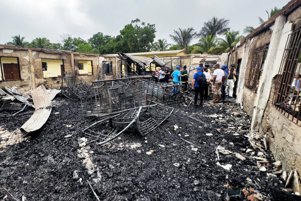 DUST AND ASHES: Investigators and government employees inspect the school dormitory on Monday, after a fire killed at least 19 people in Mahdia, Guyana on Sunday night. AFP PHOTO  - 