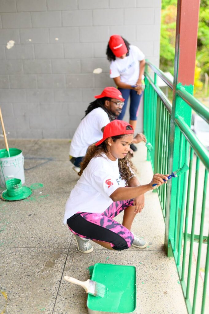 GIVING BACK: Scotiabank employees paint railing at the Matura Government Primary School as part of United Way's National Day of Caring. PHOTO COURTESY SCOTIABANK - 