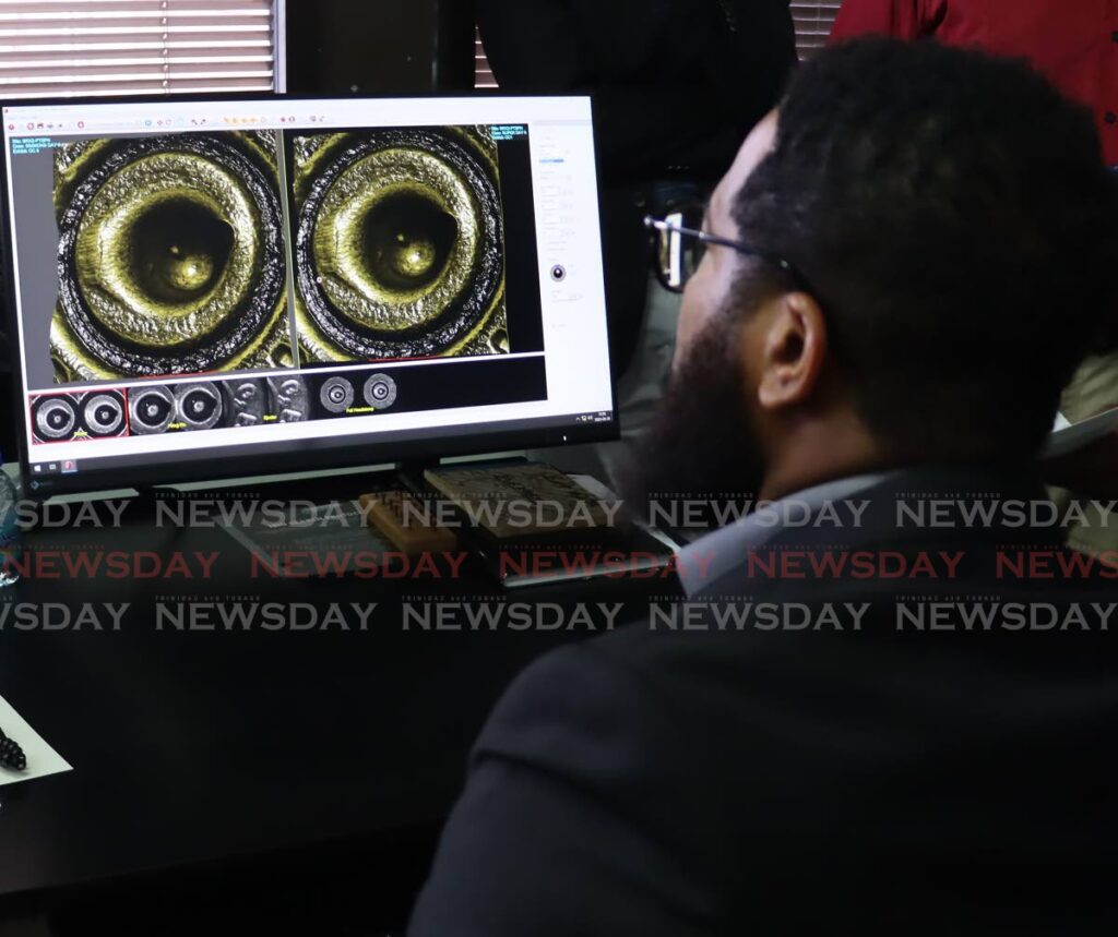 One of the certified ballistic experts demonstrate the comparision of ammunition at the Forensic Science Centre, in Port of Spain on May 26. - ROGER JACOB