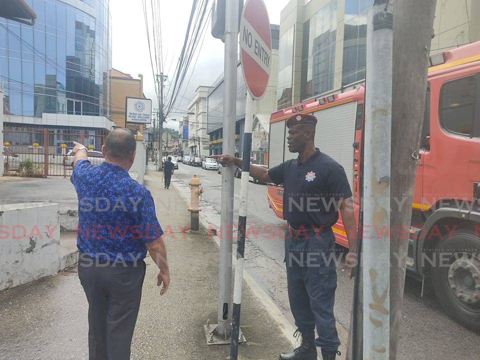 A fire officer at the corner of Duke and Edward Streets, Port of Spain, tells a pedestrian the street has been blocked off as police search the Port of Spain Magistrate's Court, after a bomb threat on Monday morning.  - Shane Superville