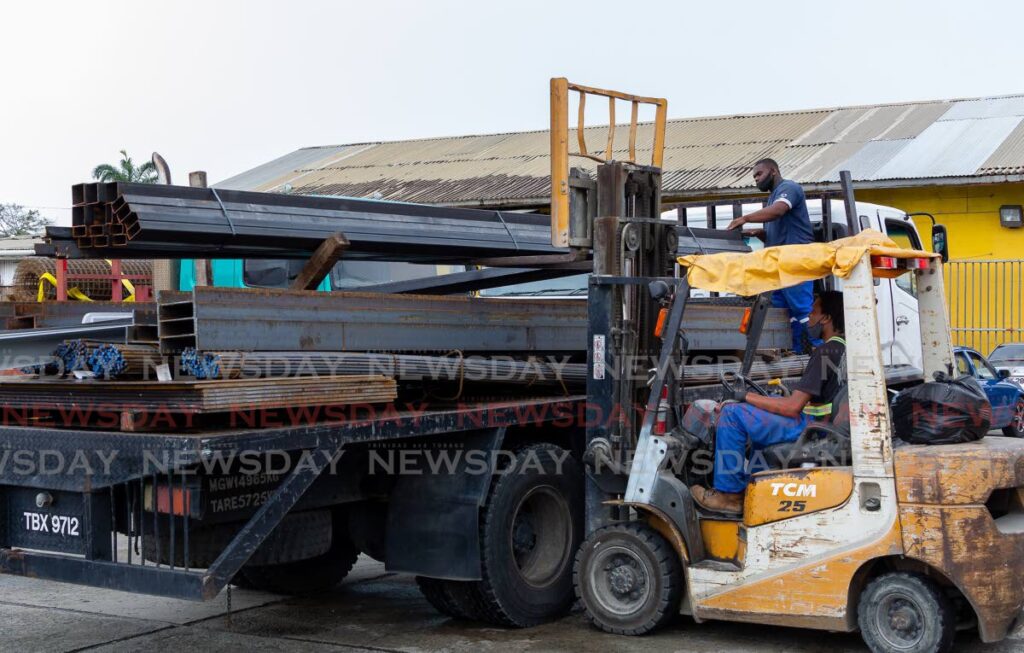 Employees at a Tobago hardware load pipes and steel beams on a truck for a delivery.
 - File photo/David Reid