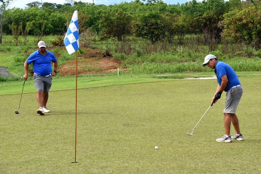 Gerard Viera makes a putt on the 17th hole to bring his team one step closer to winning the Brechin Castle Golf Club Indian Arrival Day Tournament in Couva on Tuesday. Looking on in his teammate Jonathan Augustus.  - Courtesy CJ Communications