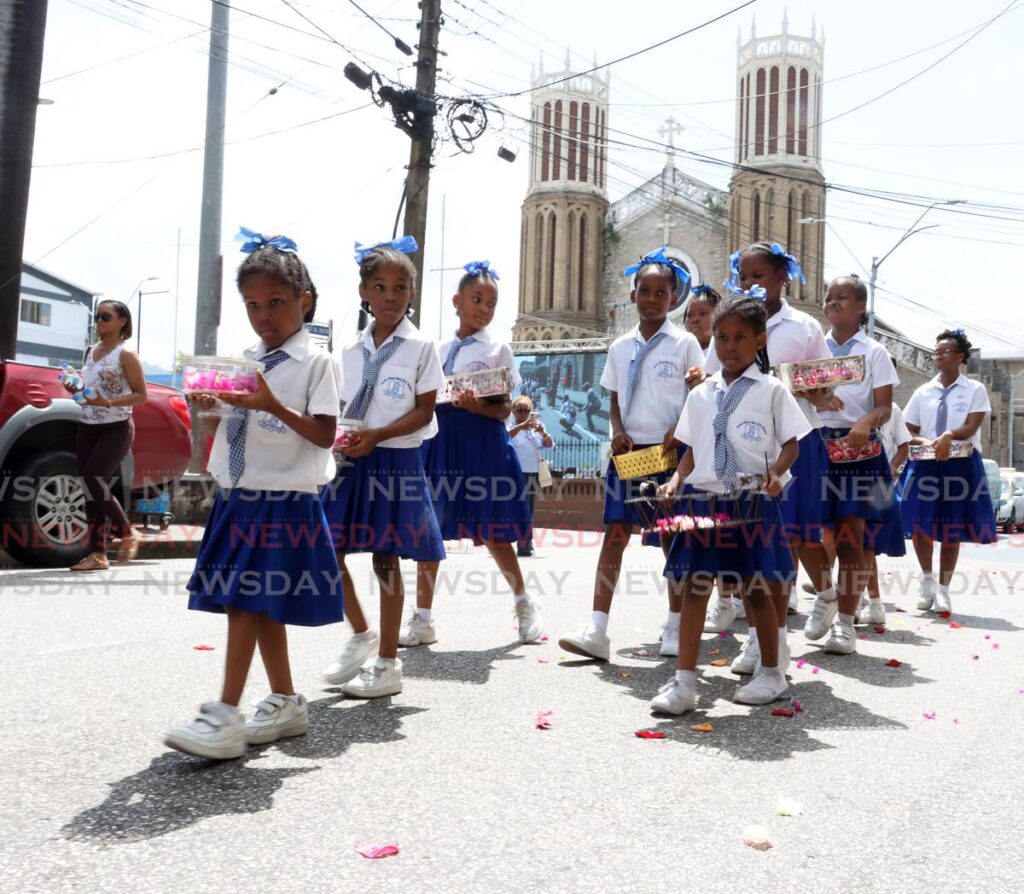 Children in their school uniforms throw flower petals on the road during the Corpus Christi procession along streets in Port of Spain. - File photo by Roger Jacob