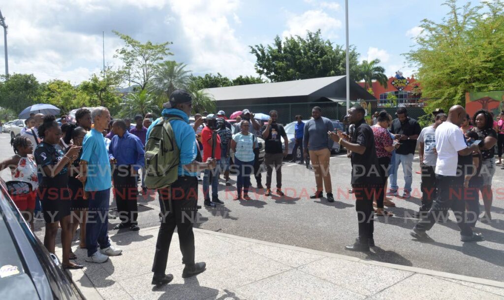A security guard speaks to disappointed members of the public outside Invaders Bay Tower, Mucurapo, Port of Spain, on Friday after the cancellation of the launch of Star Network's Blue Mobile Network on Friday morning. - Anisto Alves