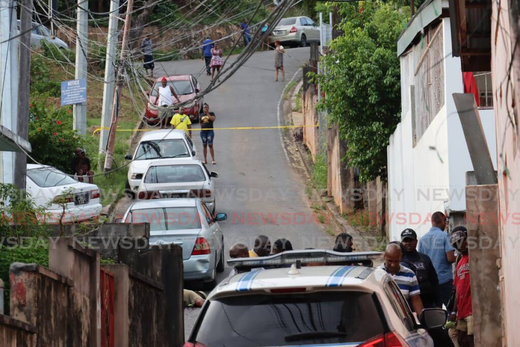 Residents look on as police and crime scene investigators secure the site and collect clues at the scene of a double murder at Davis Street, Belmont, Port of Spain on Friday at which brothers Raymond and Andy Weekes were killed by gunmen - ROGER JACOB