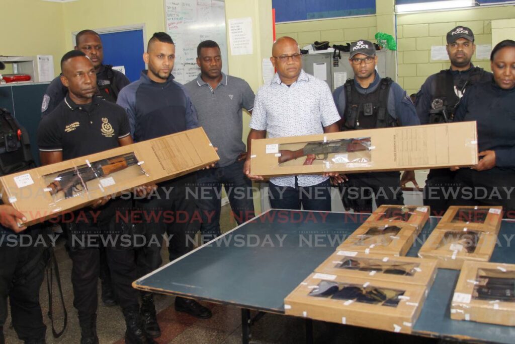 Snr Supt Richard Smith, centre, and Southern Division officers display four guns and magazines seized from a Venezuelan in Debe at Marabella Police Station on Saturday. - Lincoln Holder