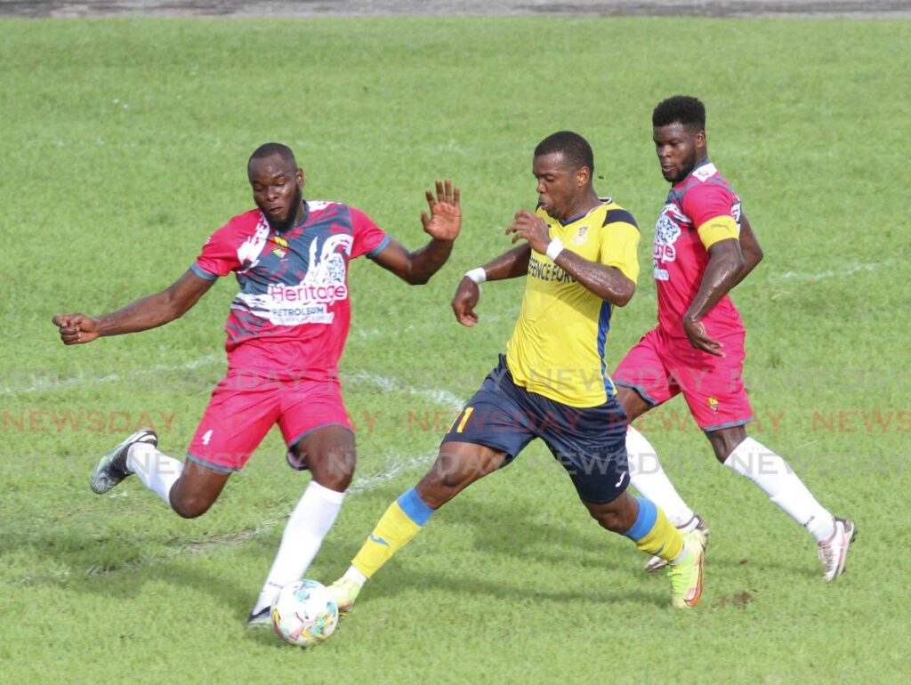 Andre Ettienne of Heritage Petroleum Point Fortin, left, puts in a crunching take on Dwight Quintero of Defence Force FC, in their Premier League football match at the Arima Velodrome recently. - 