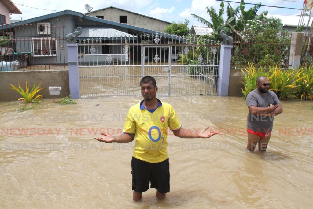 Men stand in the flooded streets of Woodland on Tuesday. - ANGELO MARCELLE