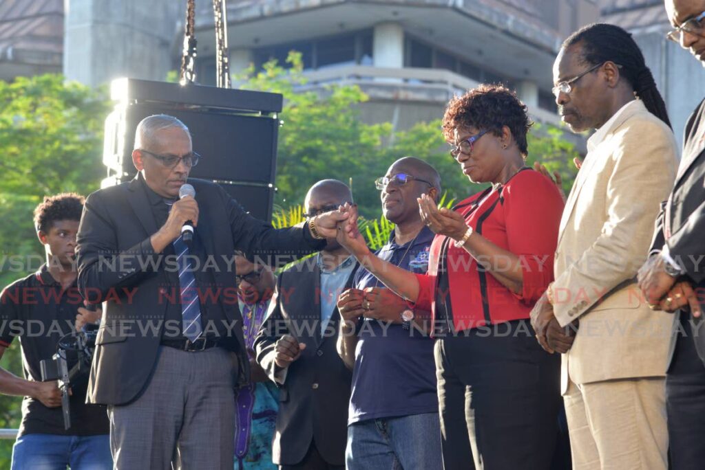 Pastor Victor Jogee, holds the hand of Commissioner of Police Erla Harewood-Christopher as he prayer for her and National Security Minister Fitzgerald Hinds at a national day of prayer event at Woodford Square, Port of Spain, on Monday. - Anisto Alves