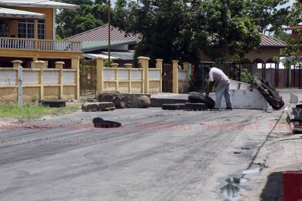 A resident blocks St Croix Road, Barrackpore, in protest on Tuesday. - Lincoln Holder