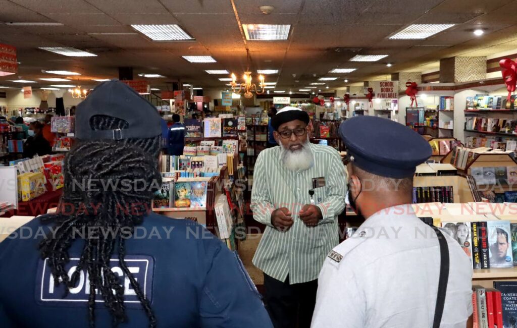 Police listen to Umar Abdullah on his objections to a book about a LGBT+ character at RIK bookstore, San Fernando on Thursday. - Roger Jacob