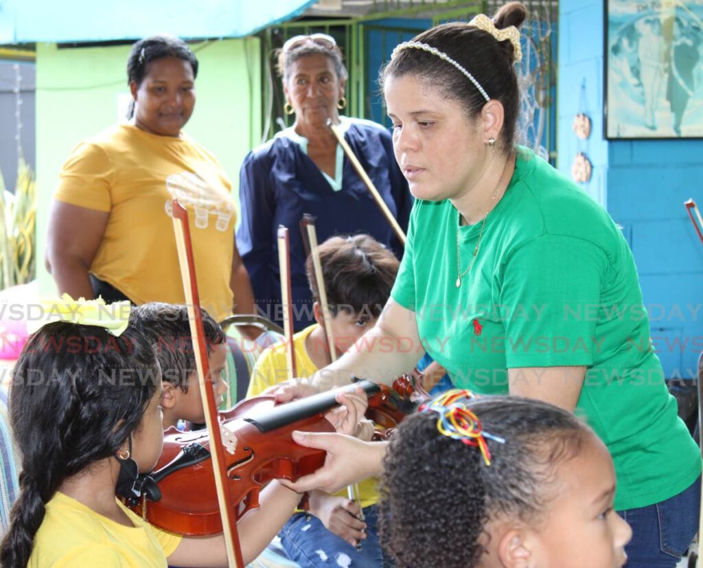 Venezuelan teacher Elid Matute shows her students how to hold the violin.