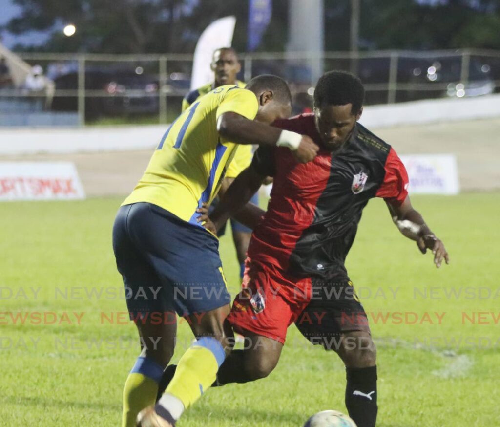Dwight Quintero (L) of Defence Force FC and Maurice Ford of Athletic Club Port of Spain, challenge for the ball in the final of the TT Premier Football League at the Arima Velodrome, Arima on Saturday. - 