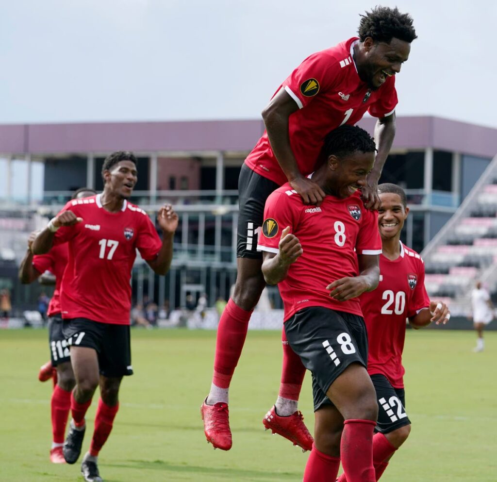 Trinidad and Tobago defender Triston Hodge jumps on teammate Ajani Fortune after Fortune scored vs St Kitts during a CONCACAF Gold Cup match, Sunday,  in Fort Lauderdale, Florida. - AP