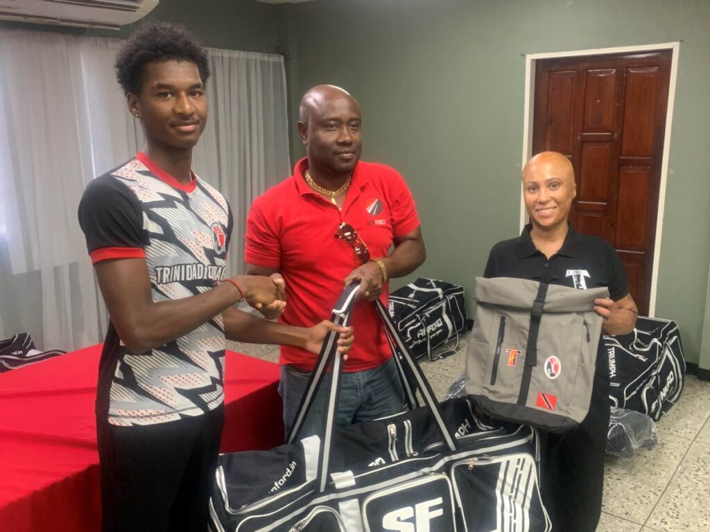 Cricketer Jacen Agard, left, collects his equipment bag, courtesy 360 Cricket, from TT U-19 team manager Kerwin John,  while Justine Low, sponsorship manager of Tribe Carnival provided backpacks and helmets for the players, ahead of their trip to St Vincent for the CWI Rising Stars Regional Tournament.  - 