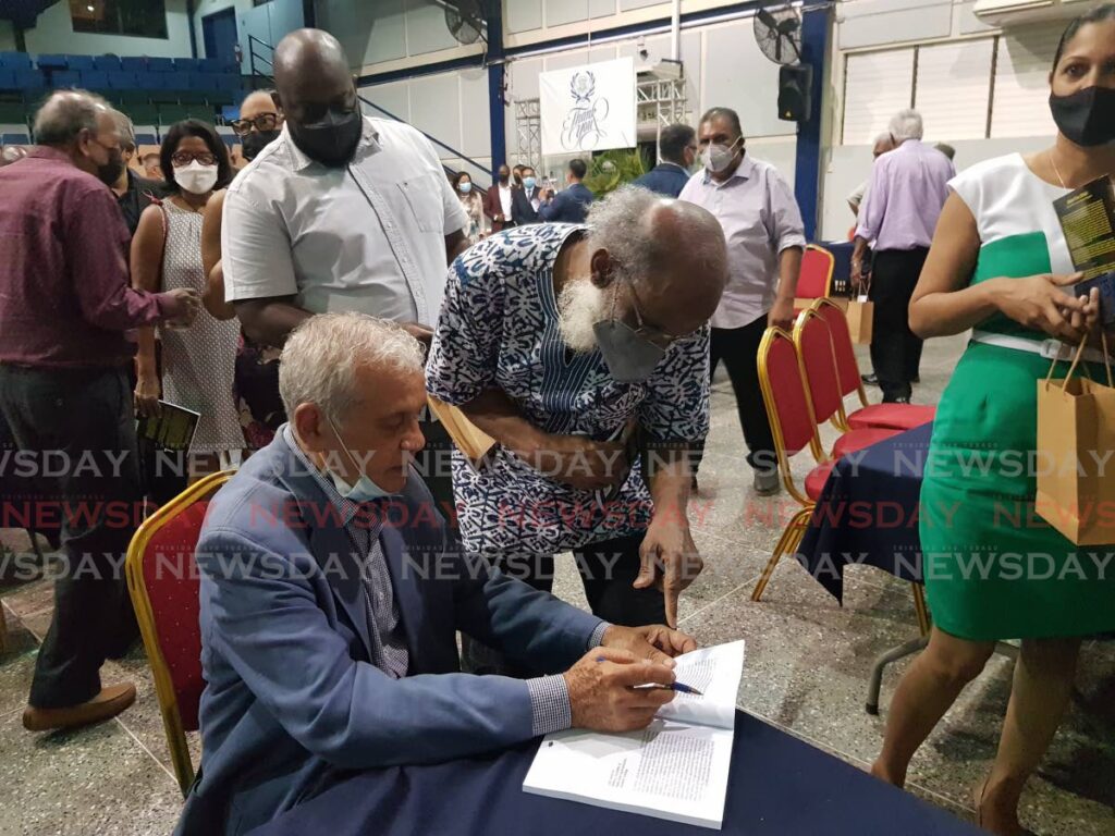 Professor Emeritus Dr Brinsley Samaroo, seen in this May 14 photo signing a book for Khafra Kambon of the Emancipation Support Committee. Samaroo died on Sunday at age 84. FILE PHOTO - 