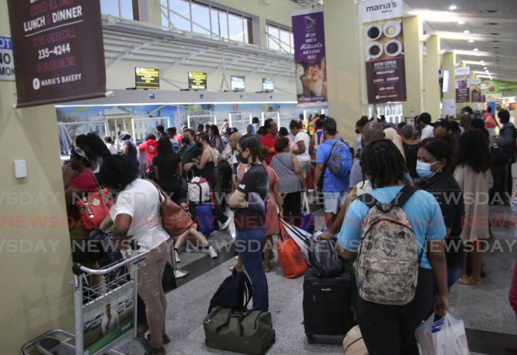 Passengers bound for Tobago crowd the ticket counter after flight delays at Piarco International Airport in 2022. - 