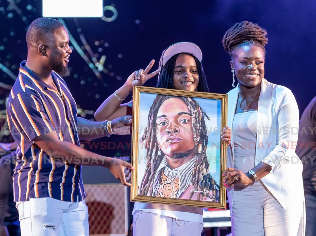 Secretary of Tourism Tashia Burris, right, presents Jamaican reggae artiste Koffe, centre, with a portrait done by Shamari Richardson, at the International Jazz Festival, Tobago in April.  - File photo/David Reid