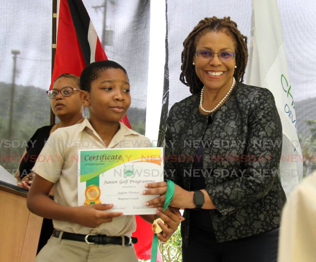 St Peter's RC student Jaylon Thomas receives a certificate from Marie Hinds, acting permanent secretary, Ministry of Planning and Development at Chaguaramas Golf Course on Friday. - 