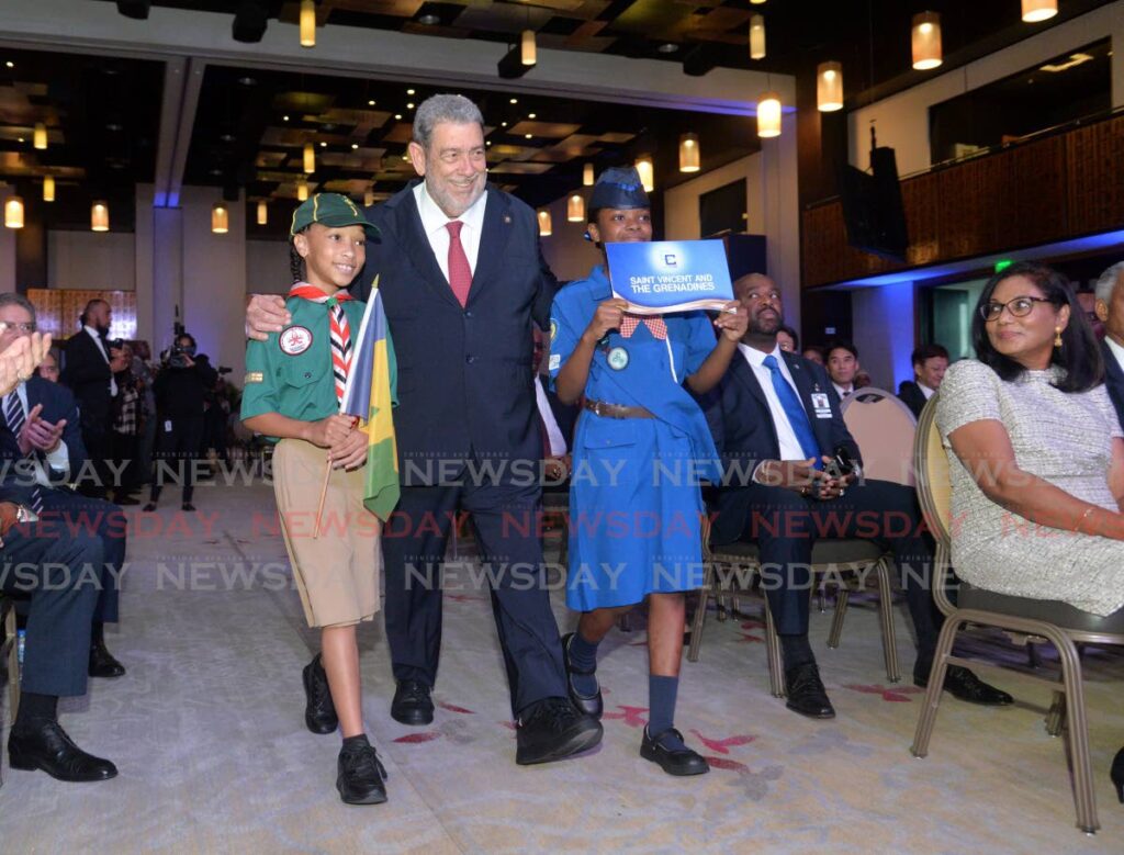 St Vincent Prime Minister Dr Ralph Gonsalves is escorted by a scout and girl guide at the opening ceremony of the 45th Caricom Heads of Government Meeting, Hyatt Regency, Port of Spain on July 3. - Photo by Anisto Alves