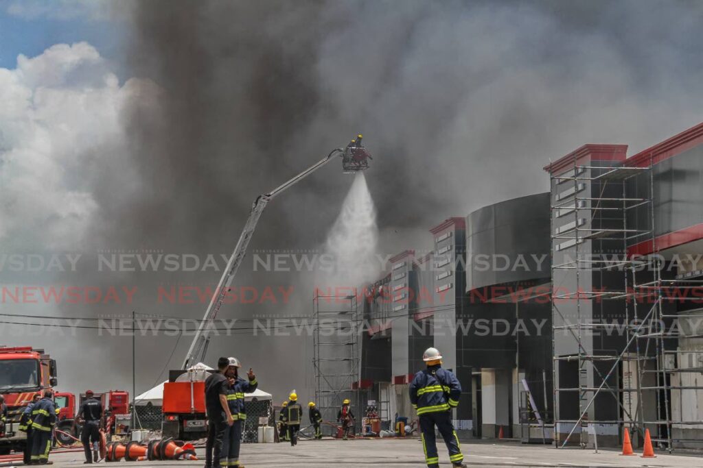 Firefighters use a sky lift in an attempt to douse a fire at Dansteel Ltd in La Romaine, on Thursday. - AYANNA KINSALE