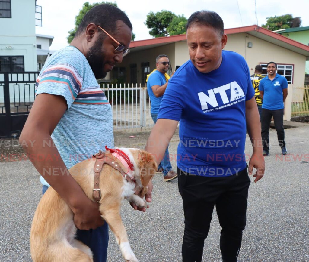 'DOH BITE MEH': NTA leader Gary Griffith, right, pets Kuddles the dog who is held by Kevon Lewis during Griffith's walkabout in Barataria on Monday. PHOTO BY ANGELO MARCELLE   - 