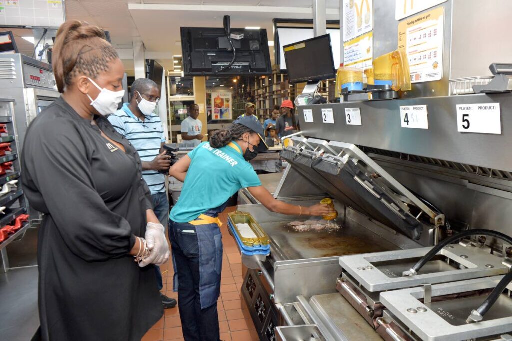 Kalifa Duncan, Market Manager, McDonald’s Trinidad looks on as a chef puts the final touches on the new tasting burger.