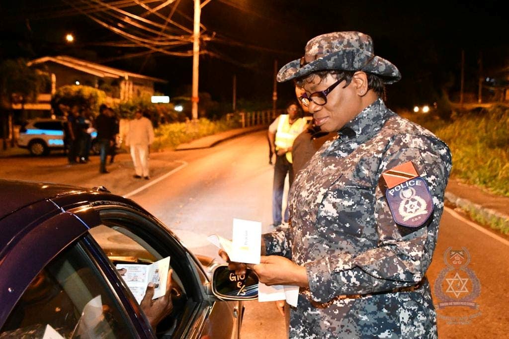 Police Commissioner Erla Harewood-Christopher examines the documents of a motorist during her tour-of-duty with her fellow officers in different police districts on Saturday night. - TTPS