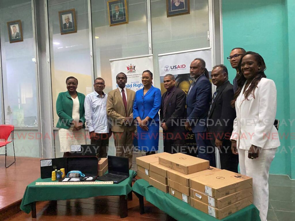 USAID, IOM and Gender and Child Affairs officials, along with National Security Minister Fitzgerald Hinds and Minister with responsibility for Gender and Child Affairs Ayanna Webster-Roy pose in front of laptops to be donated to the Home for Migrant Girls.  - Narissa Fraser
