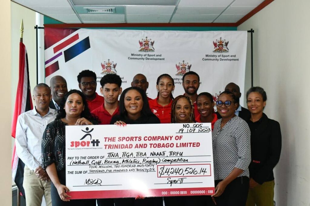 Minister of Sport and Community Development Shamfa Cudjoe, middle, presents a cheque to members and athletes of sporting bodies. - courtesy Ministry of Sport and Community Development