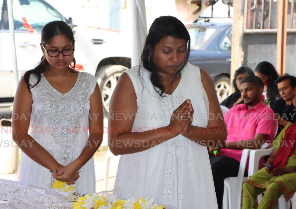 Nalini Lal, left, and Radha Lal, granddaughter and daughter, respectively, of murdered pensioner Lutchmin Bickram, perform final rites at her funeral at her home at Singh Avenue, Calcutta #2, Freeport on Thursday. - Angelo Marcelle