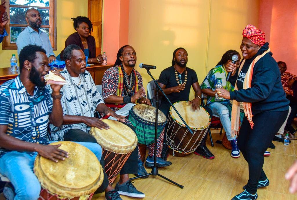 A vocalist is accompanied by African drummers. - 