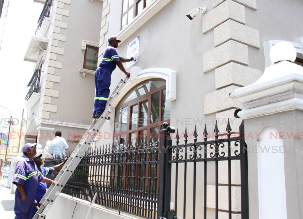 A maintenance worker places a For Rent sign on Pembroke Place which the THA had rented for use as office in Trinidad but never occupied. - AYANNA KINSALE